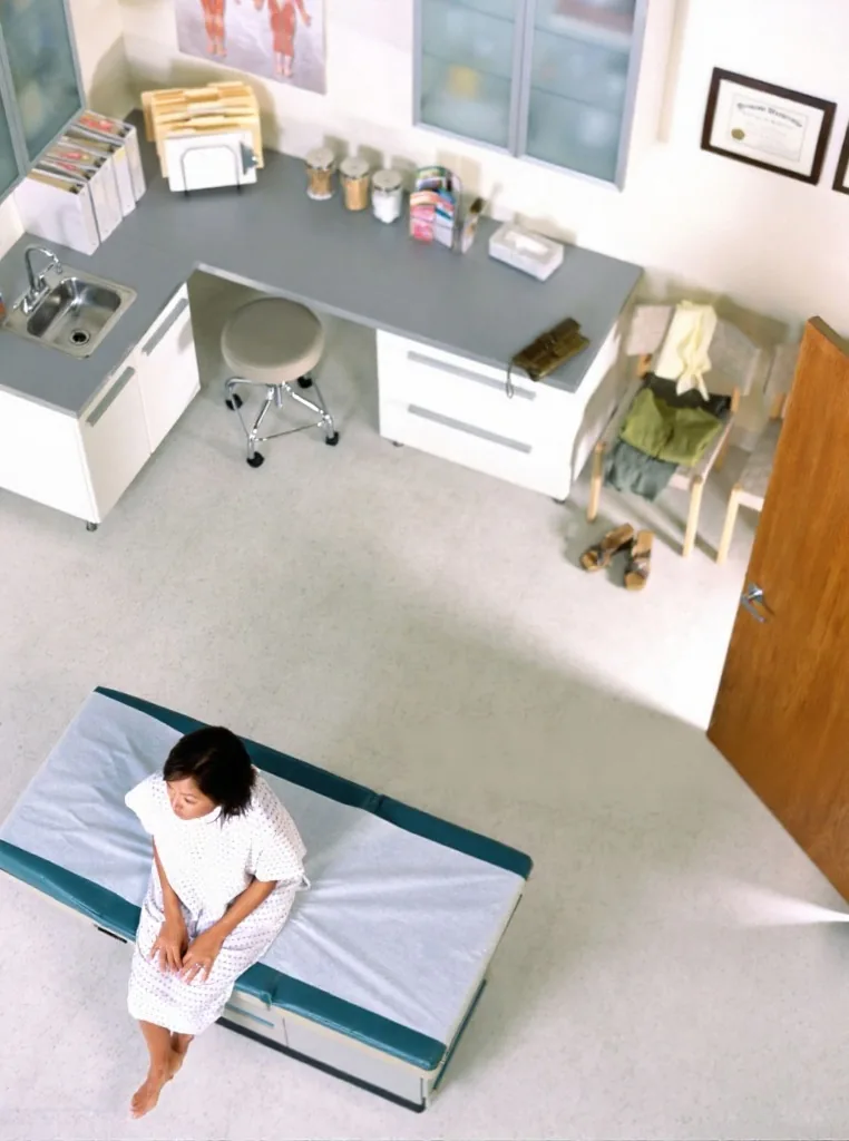 A patient sitting alone on the table in an empty exam room